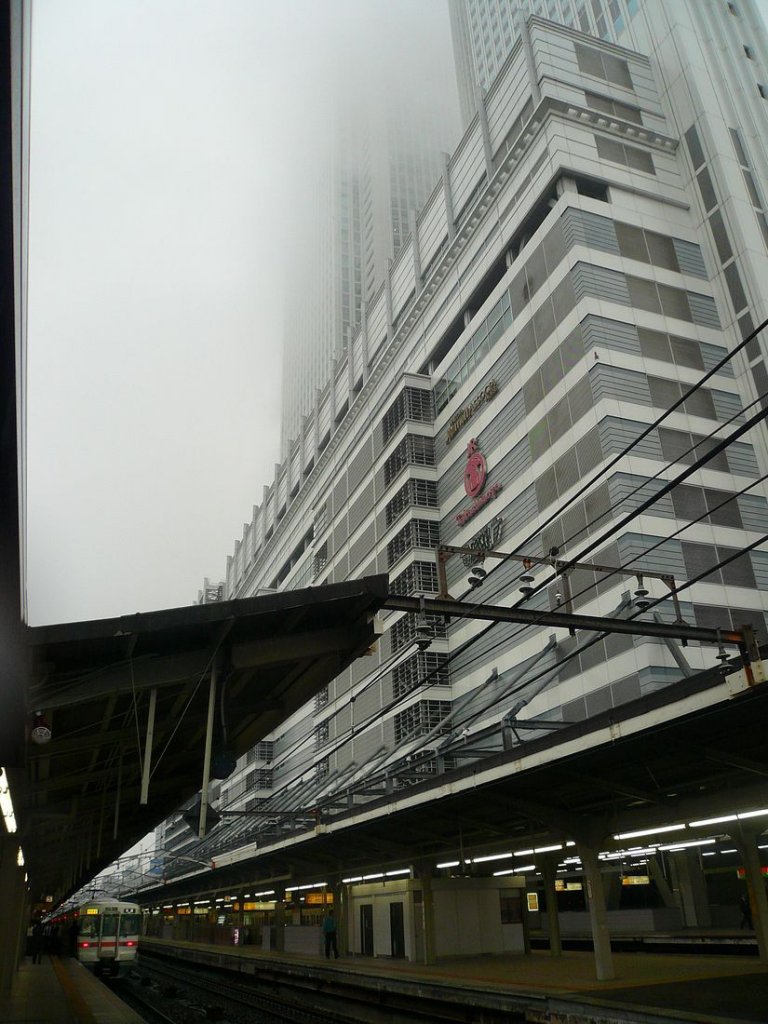 Serie 313 im Hauptbahnhof Nagoya: Wo ist der Zug? Ein Taifun wälzt sich auf Nagoya zu; schon haben seine schweren Sturmwolken die Hochhäuser am Bahnhof erreicht. Darunter wartet ein Zug Serie 313 in der erdrückenden Dunkelheit auf Abfahrt. 2.Oktober 2009. 