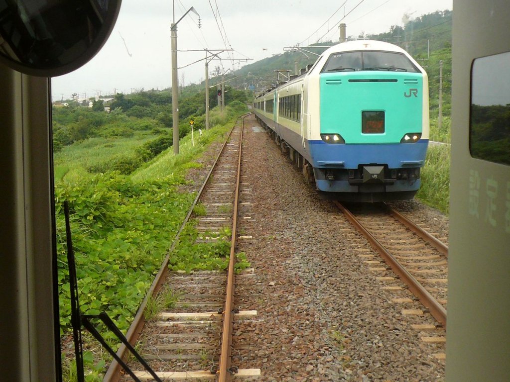 Serie 481 / 485-3000: 1996-2001 wurde eine Anzahl Züge sehr umfassend modernisiert; die Züge mit der grünen Front bilden nun das Rückgrat des Intercity-Verkehrs in den äussersten Nordwesten der Hauptinsel hinauf. Im Bild kommt bei Nishime (südlich der Stadt Akita) ein Zug mit Frontwagen KUHA 481-3043 entgegen. Die üppige Vegetation auf den Gleisen fällt auf. 10.Juli 2010.
