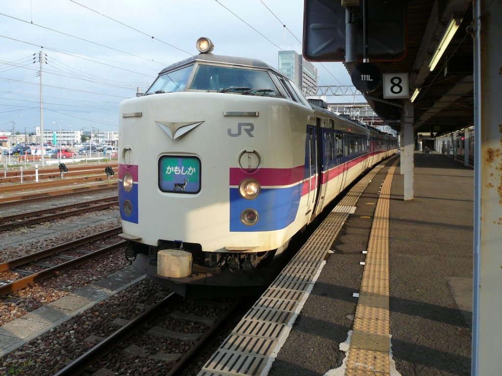 Serie 481 / 485: Ein zur Dreiwageneinheit reduzierter Zug für den leichten Städteverkehr im äussersten Nordwesten der japanischen Hauptinsel. Der Intercity  Kamoshika  (eine grosse Gemsenart, die in dieser Region häufig ist; an der Front des Zugs abgebildet!) wartet in Akita auf Abfahrt nach Aomori; er besteht aus einem motorisierten Wagenpaar (Frontwagen KUMOHA 485-1006) mit Steuerwagen. 10.Juli 2010. 
