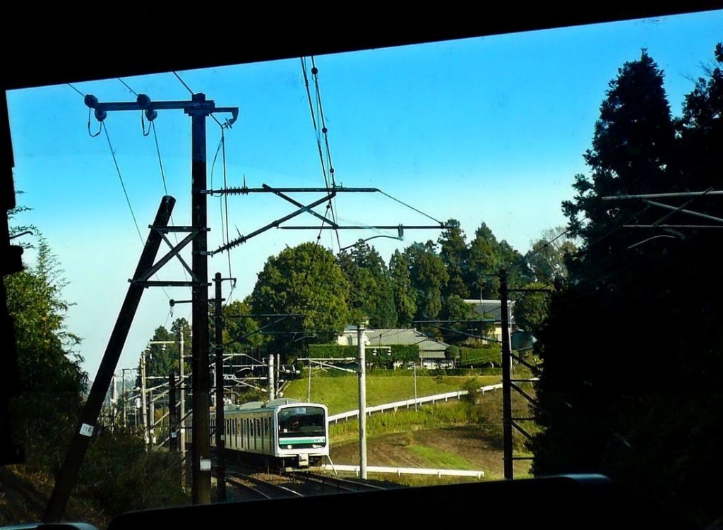 Serie 501: Ein 5-Wagenzug (Frontwagen KUHA E501-1001) begegnet in der grünen Landschaft zwischen Kandatsu und Takahama auf der Jôban-Linie Richtung Mito. 26.November 2009. (Aufnahme durch verglaste Führerstandsrückwand eines Gegenzugs)