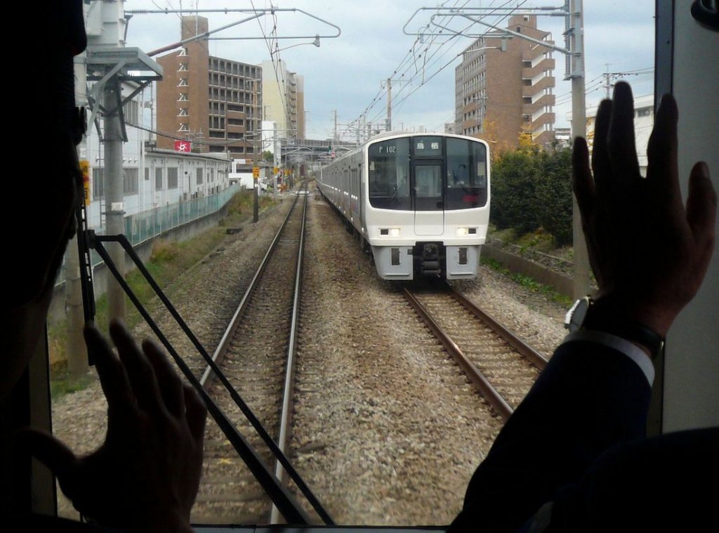 Serie 811 - Begegnungen: Doppelter Gruss - alle an der Zugspitze mitfahrenden Personen sind verpflichtet, gemeinsam dieselben Rufe (z.B.  Ausfahrsignal frei! ) und dieselben Handzeichen zu machen; so konzentrieren sich alle gemeinsam auf die Sache. Im Bild: Begrüssung des entgegenkommenden Zugs mit KUHA 810-102 an der Spitze. Takeshita, 28.November 2010. (Aufnahme durch die verglaste Führerstandrückwand) KAGOSHIMA HAUPTLINIE (NORD)