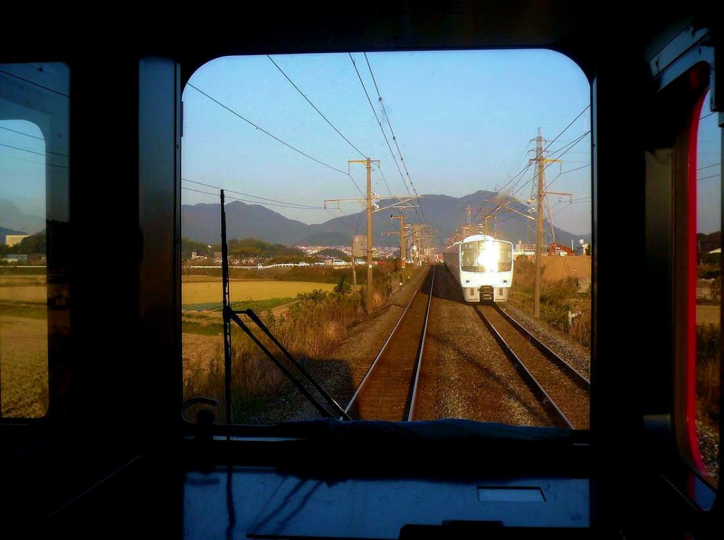 Serie 811: Direkt in die untergehende Dezembersonne hinein fährt der Zug mit KUHA 810-105 an der Spitze bei Akama an der Nordküste von Kyûshû. 1.Dezember 2010. KAGOSHIMA HAUPTLINIE (NORD)
