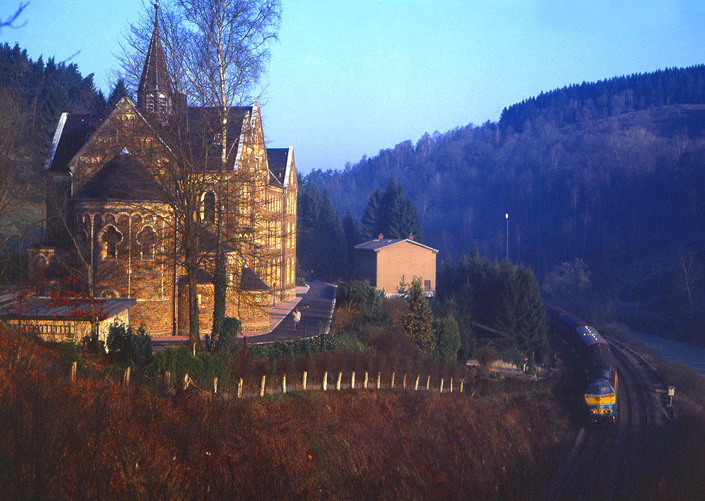 SNCB 5542 ist am 31.03.1990 mit Ex 111 unterhab des Klosters Fnfbrunnen bei Sassel zwischen Troisvierges und Clervaux unterwegs.