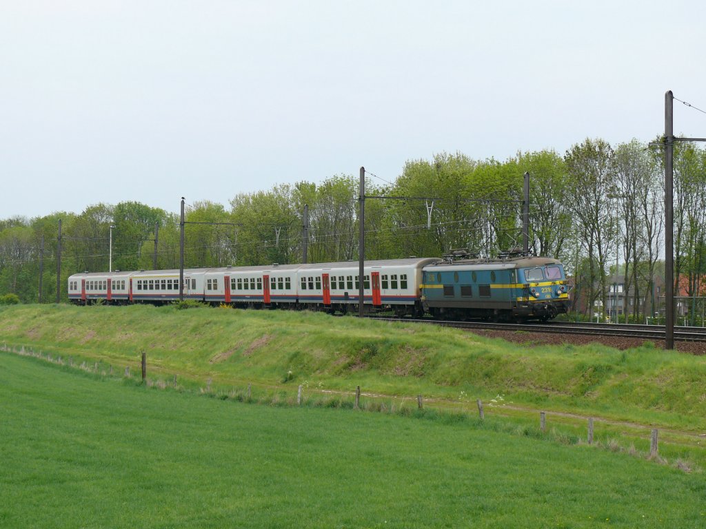SNCB-Lok 2316 (Baujahr 02/1956) kommt mit vier M4-Wagen von Antwerpen-Noord. Dieser Endpunkt wird nur fr Bahnangestellte angefahren, die dort ihren Dienst verrichten. Der Zug verkehrt jeweils zum Schichtwechsel. Trotz ihres Alters sieht man die Loks der Serie 23 noch hufig vor P-Zgen. Das Bild entstand am 14/05/2010 an der grossen Schleife bei Ekeren.