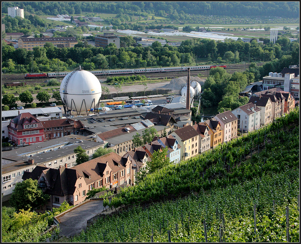 Stadtlandschaft mit Bahn - 

Zwischen Weinberge und Neckar befindet sich eine heterogene Bebauung und die Bahnlinie. In der Straße mit den schönen Hausfassaden im Vordergrund verläuft auch eine Strecke des Esslinger O-Busses. Dahinter dann Gewerbeflächen mit dem Gaskessel. Der Neckar verläuft in dem Grünbereich hinter den Bahngleisen. 

Esslingen am 22.05.2011 (M)