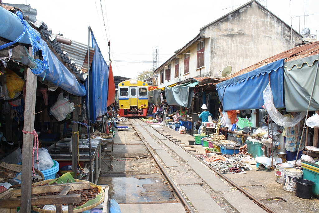 Strecken-KM 33,600, gleich beim Bf. Mae Klong am 27.März 2010. Die Strecke ist nun für die nächste Zugfahrt frei gegeben, und der nummernlose Triebwagen verlässt die Bahnhofshalle.