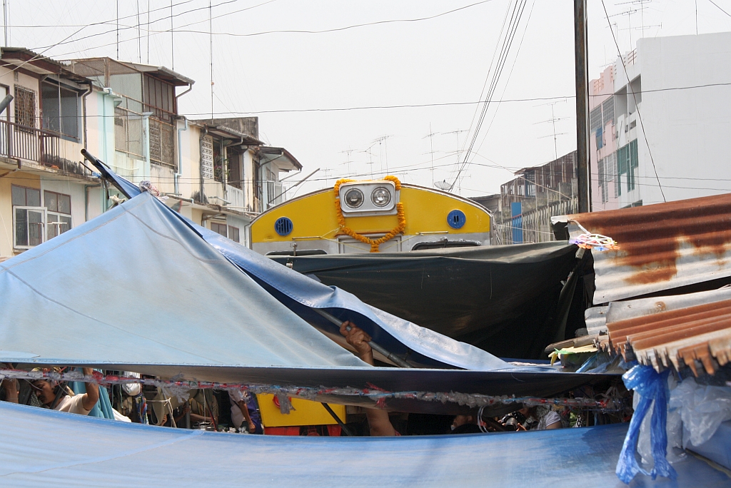 Strecken-KM 33,600, gleich beim Bf. Mae Klong am 27.März 2010. Kaum ist der Triebwagen 1213 vorbei, wird der Markt schon wieder aufgebaut.