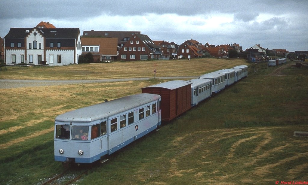 T 2 und T 4 der Inselbahn Juist verlassen im Mai 1981 den Ortsbahnhof. Der T 2 ist heute beim DEV in Bruchhausen-Vilsen als T 44 im Einsatz, während der T 4 als 187 013-8 für die Harzer Schmalspurbahnen unterwegs ist.