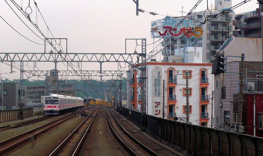 Tôkyû-Konzern (Tokyo S-Bahn), Serie 1000: Ein 8-Wagenzug mit Endwagen 1101 in Shin Maruko. Rechts Hotel Angela, ein in der Gegend typisches Hotel mit abgedunkelten Zimmern und Herzchen im Namenszug. 2.Juli 2010. 