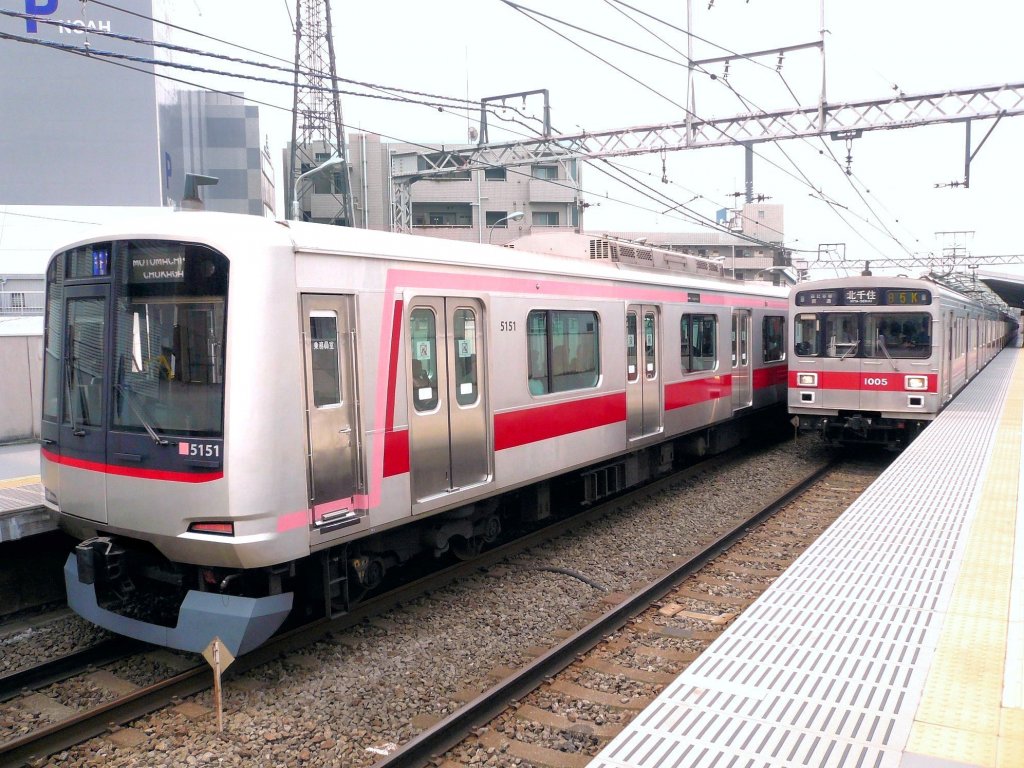 Tôkyû-Konzern (Tokyo S-Bahn), Serie 1000 (rechts im Bild): 113 Wagen, 1988-1992 gebaut; in den letzten Jahren zu 8- und 3-Wagenzügen formiert. 10 Wagen wurden ab 2009 an die Iga-Bahn verkauft, weitere an die Ueda-Bahn. Im Bild Zug mit Endwagen 1005 in Tokyo-Toritsu Daigaku; wie aus der Fahrzielangabe ersichtlich, wird er als U-Bahn (Tokyo Metro, Hibiya-Linie) Tokyo von West nach Ost unterqueren. Links steht ein moderner Einheitszug des Tôkyû-Konzerns, Serie 5000. 2.Juli 2010.   