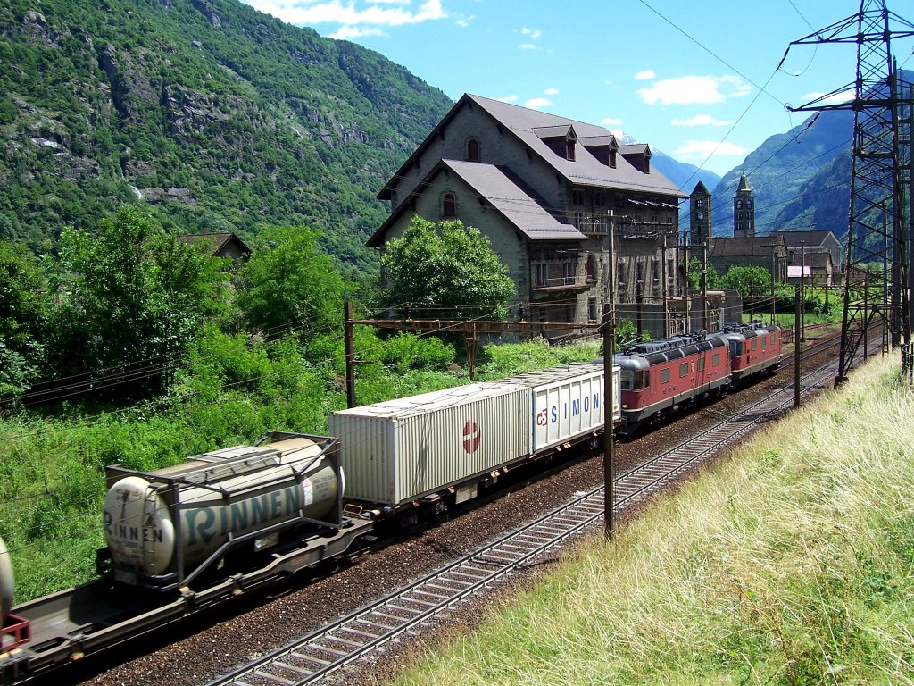 Talwrts fahrendes Re 10/10-Gespann mit Gterzug passiert gerade das Umspannwerk von Giornico. Im Hintergrund die Kirchen San Nicola und San Michele, 12.06.2009.