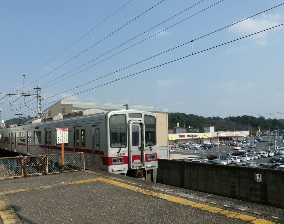 Tbu-Konzern Serie 3xxxx: Einfahrt des Zuges 31610 (gefhrt vom sechsten Wagen 36610) in der kleinen Ortschaft Yash Yamabe am Rande der Kant-Ebene. Hier knnen sich die grossen Einkaufs-Malls amerikanischen Stils ungehindert ausdehnen, und der Strassenverkehr auch. 9.Oktober 2011.