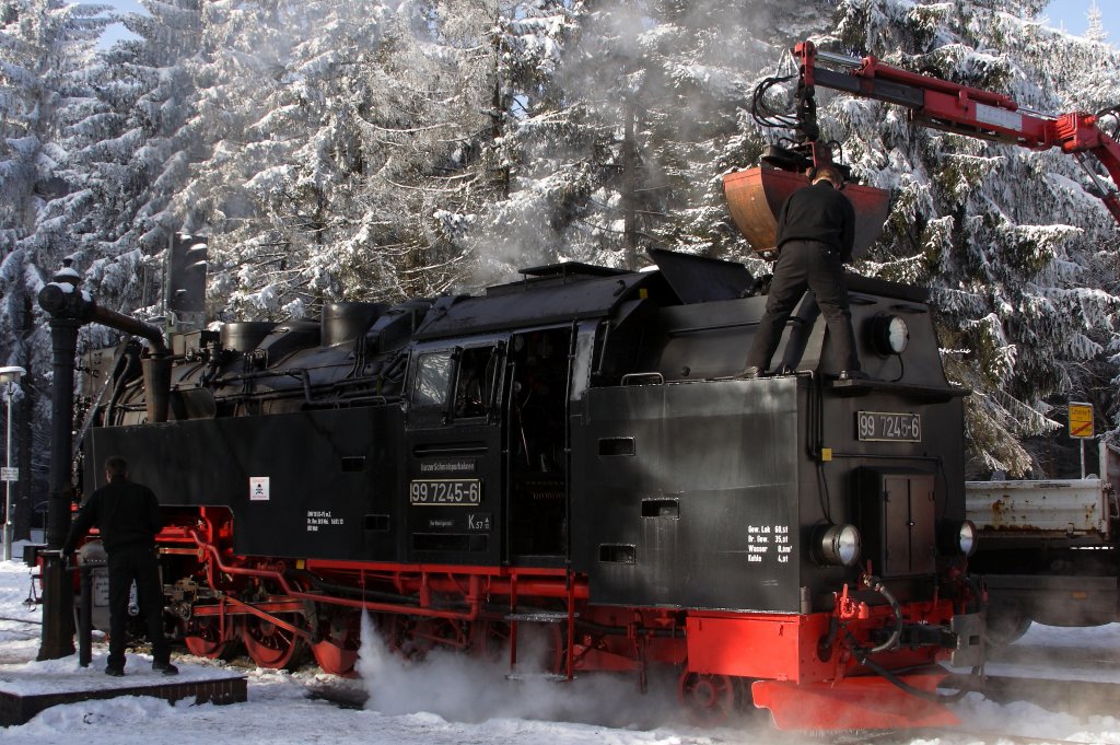 Teamwork am 26.01.2013 im Bahnhof Drei Annen Hohne! Whrend sich der Lokfhrer von 99 7245 um das Bekohlen kmmert, welches hier heute ausnahmsweise vom LKW aus erfolgt, sorgt der Heizer gerade mit dem ffnen des Absperrschiebers vom Wasserkran fr das Auffllen des Wasservorrates. In welchem Hochglanz sich die frisch hauptuntersuchte Maschine befindet, zeigt hier sehr schn die Spiegelung des linken Beines vom Lokfhrer auf dem Tender! Wenig spter geht es dann, frisch gestrkt,mit dem Sonderzug  Quedlinburger Brockenexpress  hinauf auf den sagenumwobenen  Blocksberg  (Brocken).