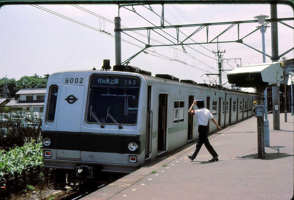 Tokyo Metro Chiyoda-Linie, Serie 6000: Zug Nr.2 (ostseitiger Endwagen 6002) in Minami Kashiwa, 2.Juli 1979. In Japan gibt es häufig starke Windstürme und entsprechend viele fliegende Mützen; der Schaffner tut etwas dagegen. 