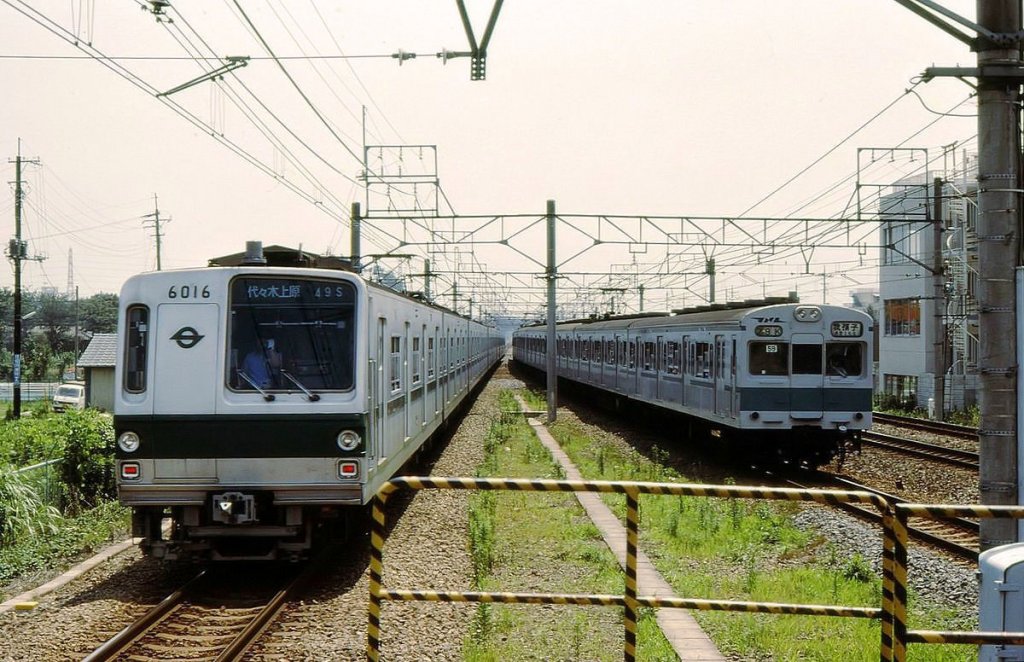 Tokyo Metro Chiyoda-Linie, Serie 6000: Links fährt U-Bahn-Zug Nr.16 (ostseitiger Endwagen 6016) gerade aus der Station Shin Matsudo aus, während rechts ein von der Staatsbahn (später JR) gestellter U-Bahn-Zug einfährt (Serie 103-1000, Endwagen KUHA 103-1017). 5.Juli 1979. 