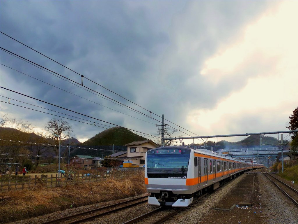 Tokyo S-Bahn, Serie 233: S-Bahnzüge aus Tokyo fahren immer weiter aufs Land hinaus und ins Gebirge hinein, je weiter sich die Agglomeration früher fast unbewohnter Gebiete bemächtigt. Hier durchfährt der Zug mit Steuerwagen KUHA 233-51 das Dorf Torisawa, bereits hoch im Gebirge westlich von Tokyo. 10.März 2013. 