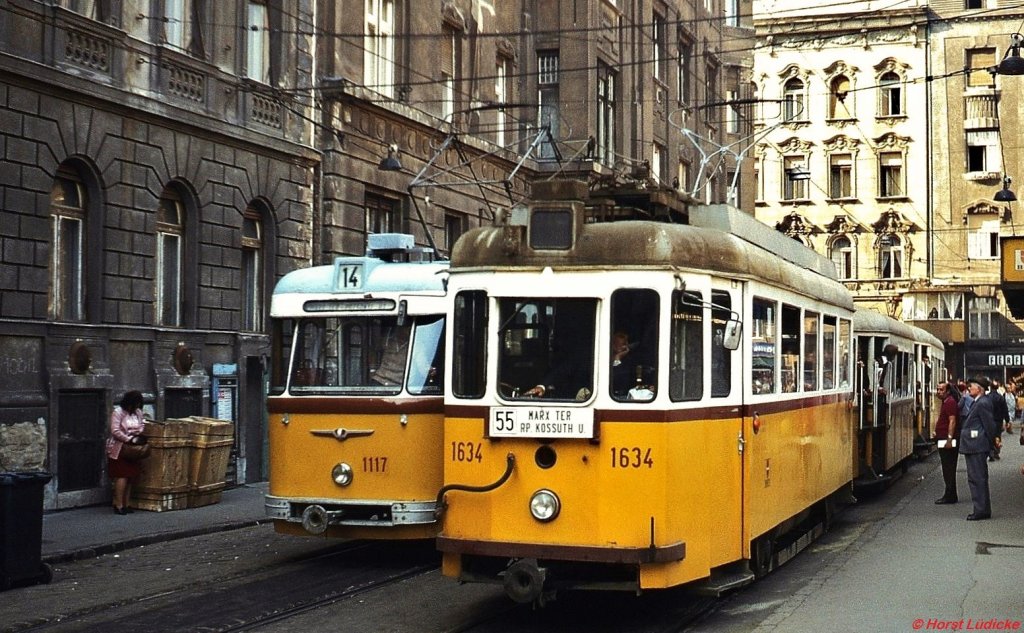 Tw 1117 (Linie 14) und Tw 1634 /Linie 55) in der Kadar utca in der Nähe des Marx ter (heute Nyugati ter). Hier endeten die aus Ujpest kommenden Straßenbahnlinien, bis sie nach der Eröffnung der U-Bahn eingestellt wurden. Der Tw 1634 (noch mit Lyra-Stromabnehmer) gehört zum Typ F/F1, die in den Jahren 1896/1897 beschafft wurde. Ab 1956 erhielten die Fahrzeuge einen Stahlaufbau, die letzten wurden 1981 ausgemustert. Tw 1117 gehört zum Typ FVV CS, diese Gelenkwagen wurden ab 1961 beschafft und bereits 1979 abgestellt.