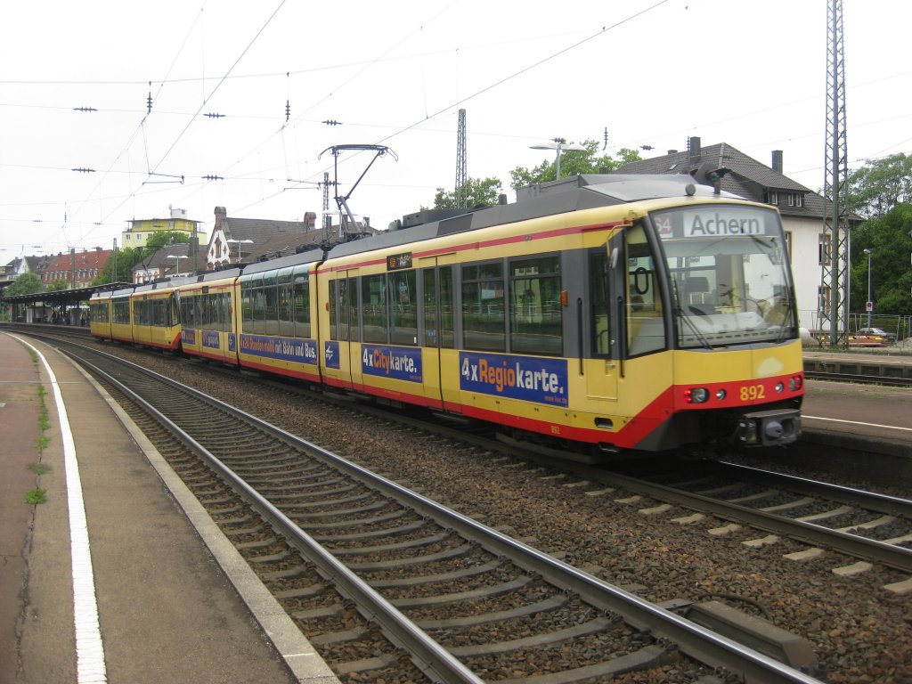 Tw 892 und der vordere Tw 918 am 20.06.2011 als S4 von Karlsruhe nach Achern. Das Duo fhrt zur Zeit in den Bf von Rastatt ein. Im Hintergrund, aber etwas durch die beiden Tw´s verdeckt: das Bahnhofsgebude und links die Bahnsteigdcher.