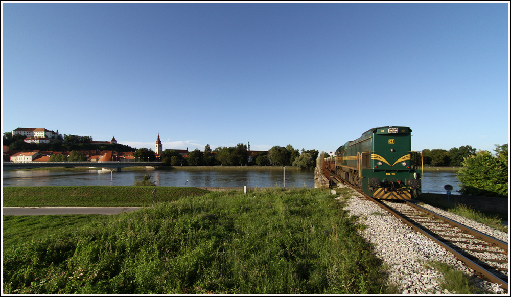 ber die Draubrcke in Ptuj, fhrt die GM Diesellok 664 113 der SZ mit einem Gterzug von nach Pragersko.
11.8.2011