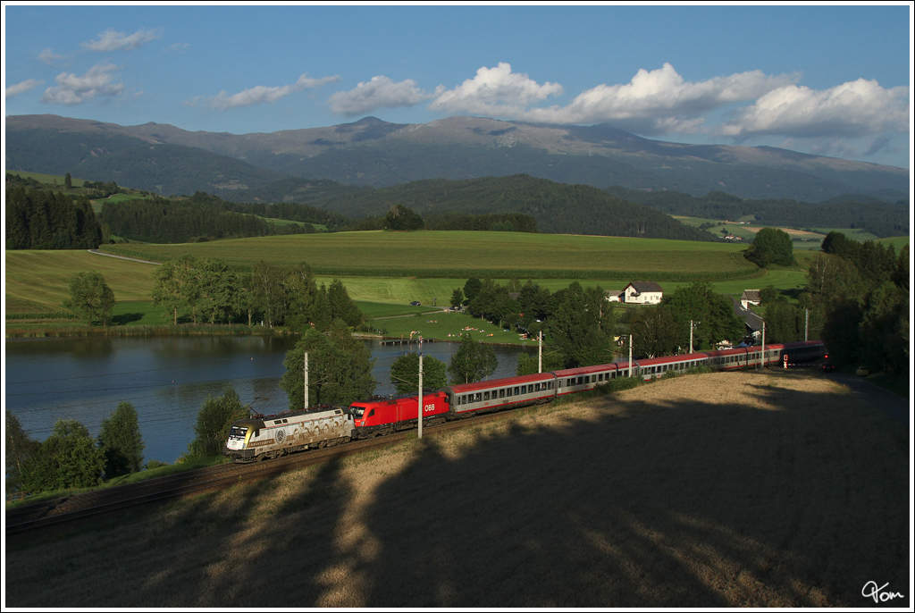 ber den Neumarkter Sattel, ziehen MAV 470 010  Aranycsapat  und 1116 275 den IC 530 von Lienz nach Wien Meidling, hier beim Furtner Teich nahe St.Lambrecht.  18.8.2012