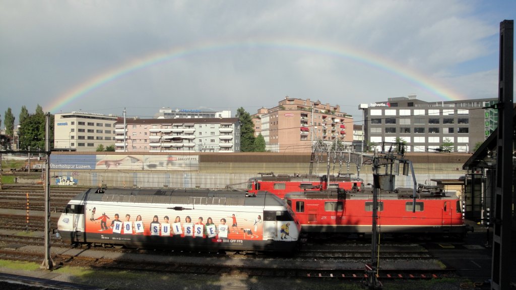 berDacht: Die Magic-Ticket-Werbelok Re 460 101-9  Hop Suisse  steht am 08.07.11 zusammen mit 2 Bo'Bo''s vor dem Luzerner Lokdepot. Das Bild ist zudem speziell, weil der Regenbogen 2 Konkurrenten des  Versicherungsgeschfts verbindet. Kommt's zur Fusion? ;)