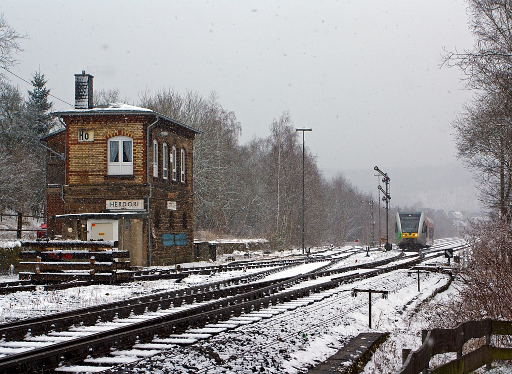 Und wieder, wie mein Freund Stefan es nennt, lsst der Winter seinen Abfall fallen - 

Ein Stadler GTW 2/6 (VT 118) der Hellertalbahn fhrt am 17.03.2013, bei Schneefall, von Herdorf weiter in Richtung Neunkirchen. 

Links ist das 1901 gebaute Stellwerk Herdorf Ost (Ho).