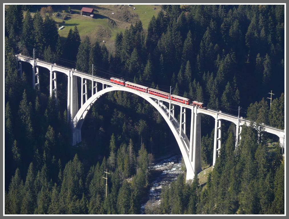 Vom Rongg 300 Hhenmeter oberhalb Langwies kann man Zug 1441 nach Arosa whrend einer viertel Stunde verfolgen. Soeben berquert er den Langwieser Viadukt. (12.10.2010)