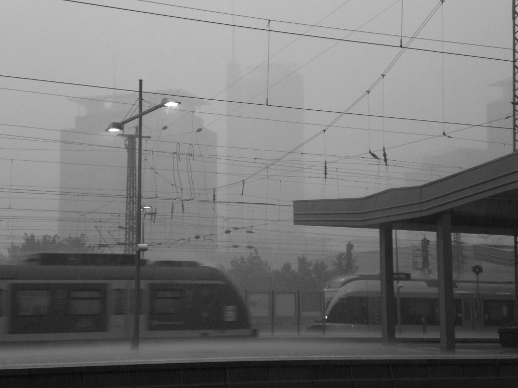 Von den Evonik Gebuden im Hintergrund des Essener Hbf ist am 03.07.2010 whrend des Niedergangs eines Gewitters nicht mehr viel zu sehen... Vorne fhrt ein ET 422 ein und rechts wartet ein Abellio FLIRT auf seine Abfahrt.