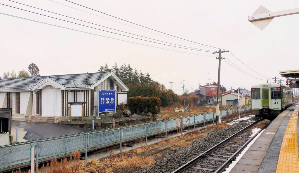 Vor dem Bestattungsinstitut  Purpurne Wolke  wartet der Einzeltriebwagen KIHA 110-125 auf Fahrgäste, die auf die noch befahrbaren paar Kilometer der Kesennuma-Linie Richtung Yanaizu wollen. Maeyachi, 15.Februar 2013.  