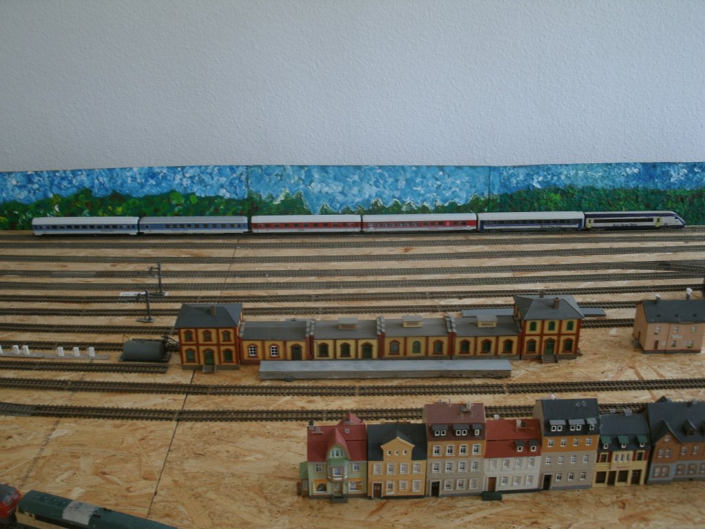 Vor der,von meiner Mutter,selbstgemalten Kulisse standen im Abstellbahnhof ein paar Wagen von einem Freund abgestellt auf meiner H0-Anlage.Aufgenommen am 27.Juli 2013.