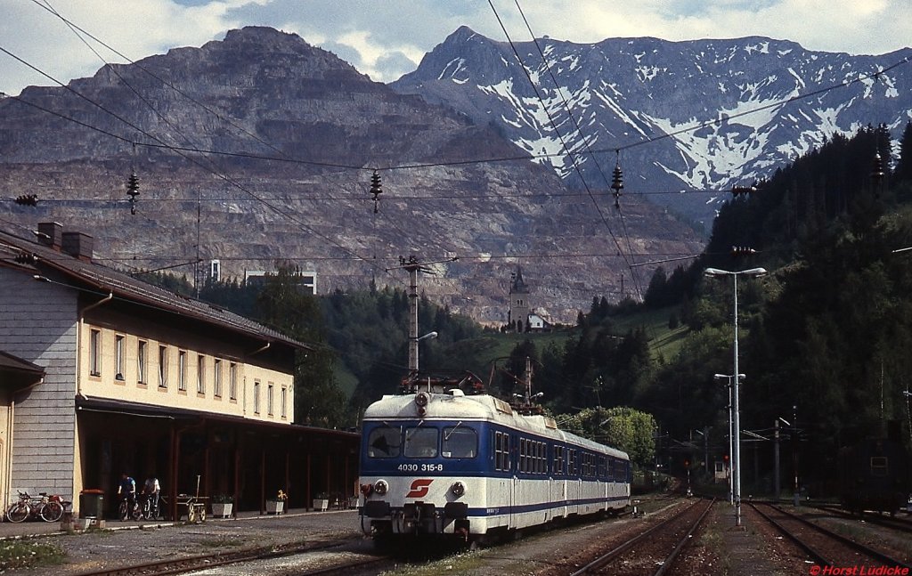Vor der Kulisse des Erzberges und des Eisenerzer Reichensteins steht 4030 315-8 im Juni 1995 abfahrtbereit im Bahnhof Eisenerz. Leider wurde auch auf der Verbindung nach Hieflau der Personenverkehr vor einigen Jahren eingestellt.