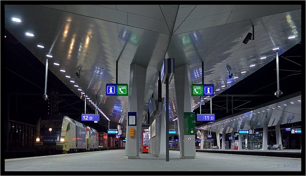 Vorsicht, Bahnsteig 12, Containerzug 43622 von Koper nach Bratislava mit der Plandurchfahrt um 01.30 Uhr, fhrt 
heute ausnahmsweise 1 Std. frher durch ... : ) WLC 182 524 & Gysev 470 505 im nchtlichen Wiener Hauptbahnhof. 
Es ist brigens gar nicht so leicht zwischen den Snack-Automaten und Wartekojen, und den kreuz und quer ins Blickfeld 
hineinragenden massiven Sttzpfeilern des Rautendachs eine gelungene Perspektive auf die Bahnsteig-Gleise zu finden ! 
Die einzige brauchbare Blickachse, ohne Sichtbarrieren auf die Bahnsteige des grauen Hauptbahnhofes, der beleuchtet 
bei Nacht, viel einladender und attraktiver wirkt, als am Tag, ergibt sich nur vom stlichen Bahnsteigende ...