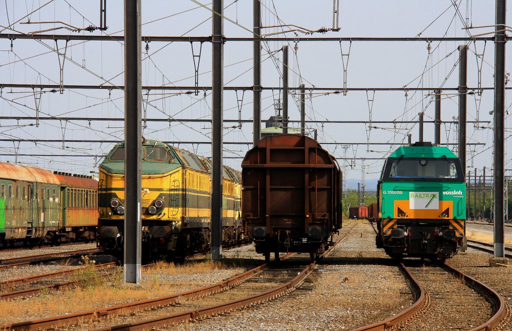 Vossloh Lok G2000BB von Railtraxx steht neben einem G�terwagen und dieser steht wiederum neben vielen alten belgischen 51er stehen in Montzen-Gare(B) bei knapp 40 Grad am 19.8.2012.