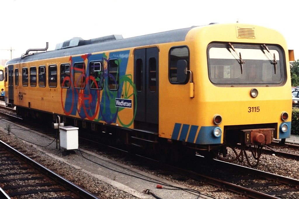  Wadfietser  3115 ist eine Triebwagen mit Fahrradteil (deshalb sind die grne, blaue und rote Fahrrder zu sehen) und steht hier in Leeuwarden am 15-8-1994. Bild und scan: Date Jan de Vries.