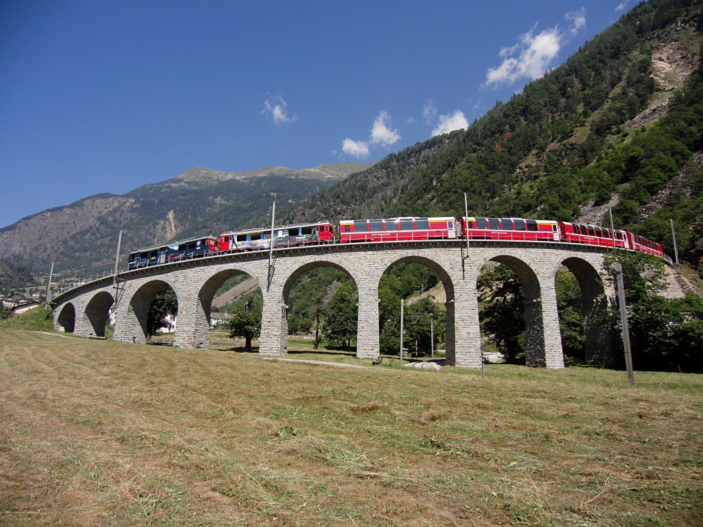 Whrend der Fotograf dieses Bildes noch eine Fotostelle fr das bekannte Motiv der Bernina-Bahn suchte, hatte sich der Mann eines jungen asiatischen Prchens bereits entsprechend positioniert. Der Bernina-Express D 973 von St. Moritz am 18.08.2012 auf dem Kehrviadukt bei Brusio hat das Ziel Tirano bald erreicht.