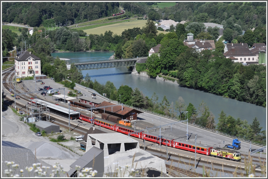 Whrend RE1233 aus Disentis mit Ge 4/4 II 611  Landquart  Reichenau-Tamins verlsst, nhert sich im Hintergrund bereits RE1124 aus St.Moritz. Die Verzweigung der Oberlnder- und der Engadinerlinie befindet sich hinter dem Zusammenfluss von Vorder- und Hinterrhein. Links der Strassenbrcke steht das Beamtenhaus und rechts davon das Schlosshotel Adler. (26.06.2011)