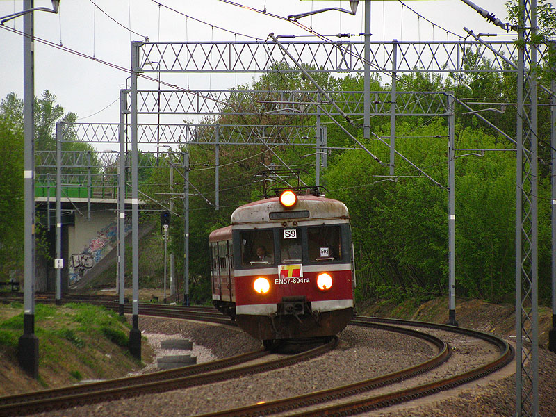 Warszawa Jelonki, 1.05.2010. EN57-804 als Zug der Linie S9 manvriert, um die Richtung zu wechseln. Mit der Linie S9 (Warszawa Gdańska - Legionowo / Legionowo Piaski) ist es wirklich kompliziert: Diese Garnitur (EN57-804) gehrt der Firma  Przewozy Regionalne , wurde aber von Koleje Mazowieckie gemietet. Fr Koleje Mazowieckie ist das ein Zug Nummer KM-6675. Er verkehrt aber als S-Bahn (obwohl S-Bahn gewhnlich von SKM Warszawa bedient wird) im Auftrag der ZTM (Warschauer Verkehrsverwaltung). Da es im Stadtverkehr keine Zugnummer gibt, ist es fr ZTM ein Zug der Linie S9, Zugesfolge 502. Und da es zur Zeit keine Mglichkeit ist, in Warszawa Gdańska zu wechseln, mssen die Zuge erst Warszawa Jelonki besuchen. Das alles gilt natrlich nur vorbergehend.