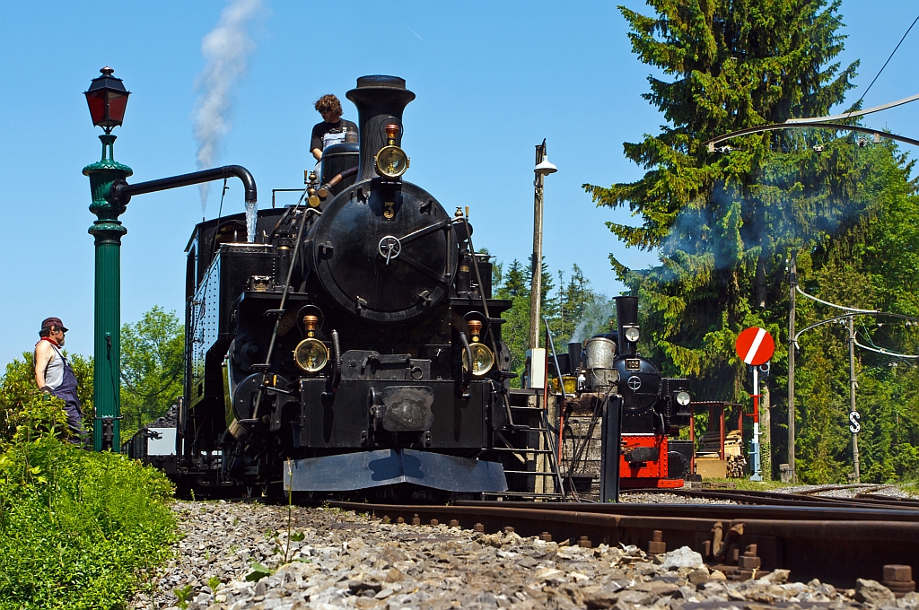 Wasser fassen der HG 3/4 Zahnraddampflok ex B.F.D.  N 3  (Brig–Furka–Disentis-Bahn) der Museumsbahn Blonay-Chamby, hier am 27.05.2012 beim Pfingstdampf Festival.
Diese Lok wurde 1913 von SLM unter der Fabriknummer 2317 gebaut. Insgesamt wurden zehn dieser Loks des Typs HG 3/4 ab 1913 durch die Brig–Furka–Disentis-Bahn beschafft. Die von der Schweizerischen Lokomotiv- und Maschinenfabrik Winterthur (SLM) gebauten Zahnradlokomotiven kamen nach ihrer Ausmusterung in der Schweiz auch in Frankreich und Vietnam zum Einsatz, diese hier kam 1969 zur Museumsbahn B-C. Bis heute sind vier Exemplare betriebsfhig erhalten, drei davon bei der Dampfbahn Furka-Bergstrecke (DFB). Weiterhin gingen berreste der der Nr. 2 und 8 Vietnam wieder zur BFD.  
Hinten rechts steht die G 2x2/2 Malletdampflok 105 der Museumsbahn Blonay–Chamby, ex 105 der Zell-Todtnau-Eisenbahn, ex  Nr. 28 Kleinbahn Voerde-Haspe–Breckerfeld.