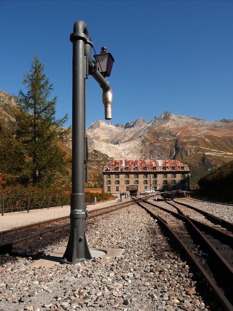 Wasserkran auf dem Bahnhof Gletsch der Furka-Bergbahn am 2.10.2011, dahinter das Blauhaus der DFB.