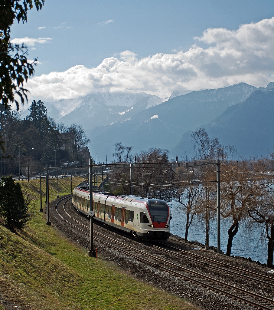 Wer sagt Gegenlicht geht nicht? Blick zu Walliser Alpen: Ein Stadler FLIRT  RABe 523 024 der SBB (RER Vaudois) als S1 (Villeneuve - Montreux -  Vevey - Lausanne -  Yverdon-les-Bains), kommt von Villeneuve und fhrt am 26.02.2012 bei  Clos du Moulin am Genfersee Richtung Lausanne.