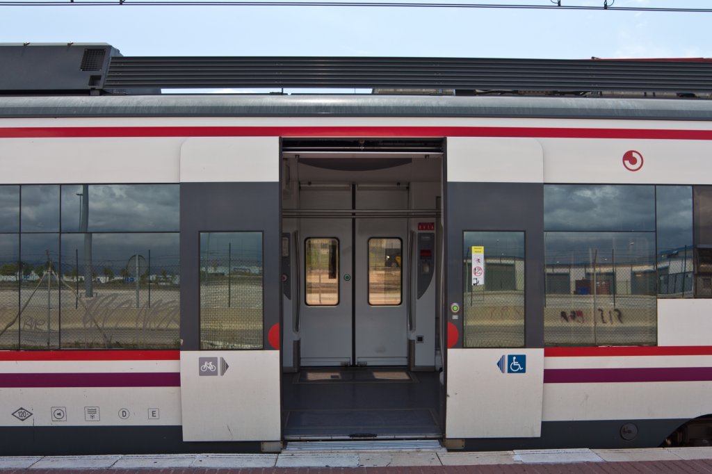 Wetternderung - whrend ber dem Zug noch blauer Himmel ist, spiegelt sich in den Fenstern schon das herannahende Unwetter. Triebzug 465-215 am 20.05.2012 im Flughafenbahnhof von Barcelona.