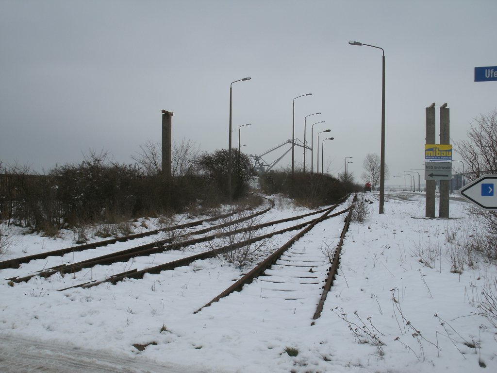 Wie ich schon berichtete plant die Thomas Meincke Eisenbahn(TME) die Reaktivierung der Greifswalder Hafenbahn nach Ladebow.Die Gleise im Hafen von Ladebow liegen seit zehn Jahren immer noch.Hier ist links ein abzweigendes Anschlugleis zusehen und das Gleis rechts endet an einer Rampe.Aufgenommen am 17.Februar 2013.