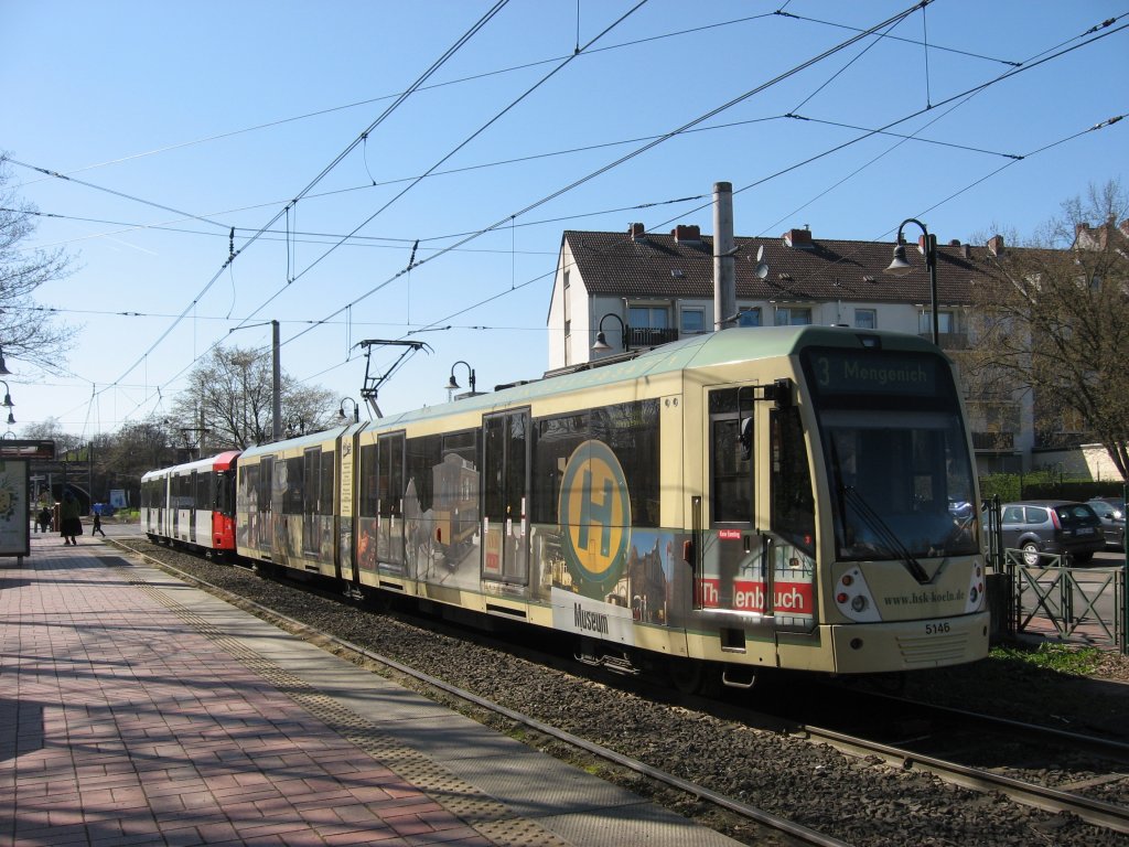 Wir schreiben das Datum des 06. April 2010 als ich TW 5146 mit seiner Werbung fr das Straenbahn-Museum Thielenbruch und einen weiteren unbekannt gebliebenen Wagen vom Typ K5000 fotografieren konnte. Besonders schn finde ich die grn-besche Farbgebung, wie frher alle Straenbahnen in Kln lackiert waren. Was ich allerdings etwas schade finde dass die Werbung nicht auf einem Stadtbahnwagen B aus der Serie 2200 oder 2300 ist, damit er auch auf den Linien 16+18, die bis Bonn fahren, eingesetzt werden kann. Der Zug im Bild stand als Linie 3 Fahrtrichtung Mengenich in der Haltestelle  Frankfurter Strae .