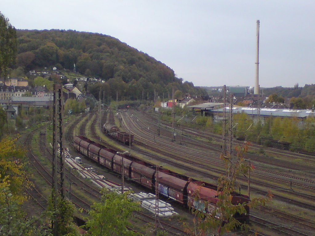 Wuppertal-Steinbeck, Blick Richtung Westen ber die Gleise der 1841 erffneten Dsseldorf-Elberfelder-Bahn. Am linken Bildrand sind im Hintergrund die Schuppen des Betriebswerkes Wuppertal-Steinbeck zu sehen. Zum Zeitpunkt der Aufnahme wurden im Hbf Wuppertal neue Weichen installiert. Im Vordergrund neben dem Kohlenzug, der das Kraftwerk mit dem hohen Schlot im Hintergrund bedient, liegen Weichenbauteile zum Einbau bereit. Das Werk Steinbeck wurde im Mai 2000 geschlossen. Am rechten Bildrand ist die Halle eines Stahlhandels mit Gleisanschluss zu sehen.