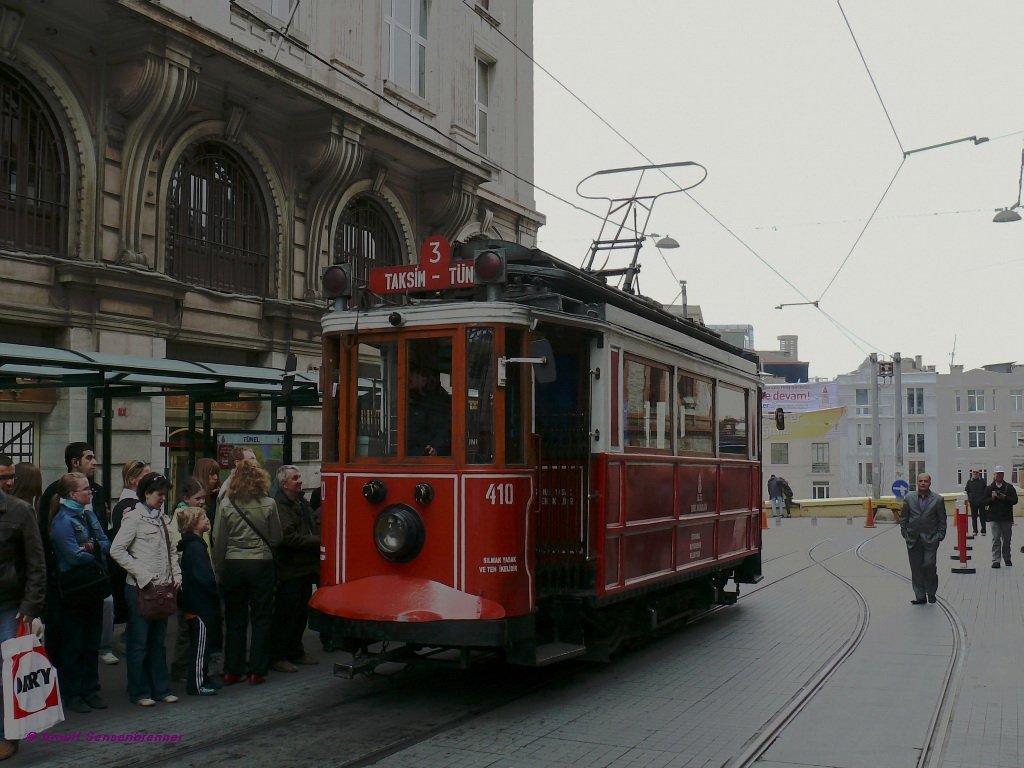 Zahlreiche fahrwillige Kunden warten hier darauf, mit Tram-Wagen 410 von Tnel nach Taksim zu fahren. Hier an der Endhaltestelle mssen die Tram und der Lyra-Bgel gewendet werden.
Die Nostaljik Tramvay ist eine 1,6 Kilometer lange Meterspur-Straenbahn, die seit 1990 durch die Einkaufsstrae (Fugngerzone) Istikll Caddesi 
zwischen Tnel und Taksim-Platz verkehrt. Hier im europischen Teil Istanbuls war die Straenbahn 1960 eingestellt worden. Sie erfllt entgegen ihrem Namen aber heute ein aktuelles Verkehrsbedrfnis.
Nur die Fahrzeuge sind tatschlich historische Fahrzeuge von 1911-1914, die bereits frher hier verkehrten und hierfr aufgearbeitet wurden.
12.04.09
