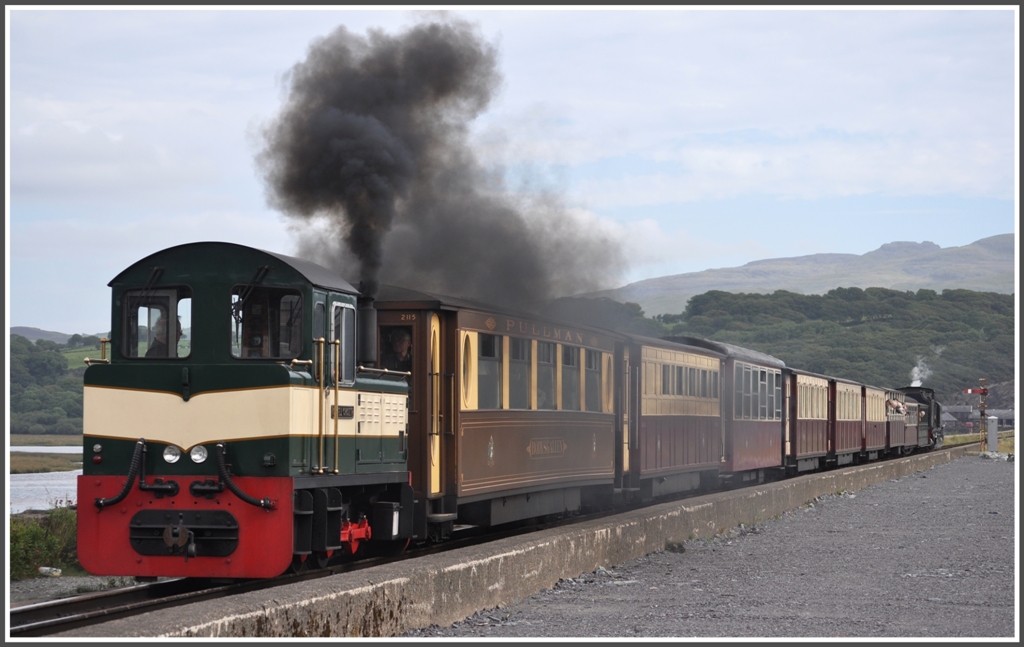 Zge der Welsh Highland Railway aus Richtung Caernarfon mssen in Porthmadog nach der Strassenberquerung am Bahnhof vorbei auf den Damm fahren, um dann rckwrts an den einzigen Bahnsteig auf der Rckseite des Gebudes zurckzudrcken. Dabei wird der Dampfzug tatkrftig von der Diesellok  Criccieth Castle  untersttzt. (04.09.2012)