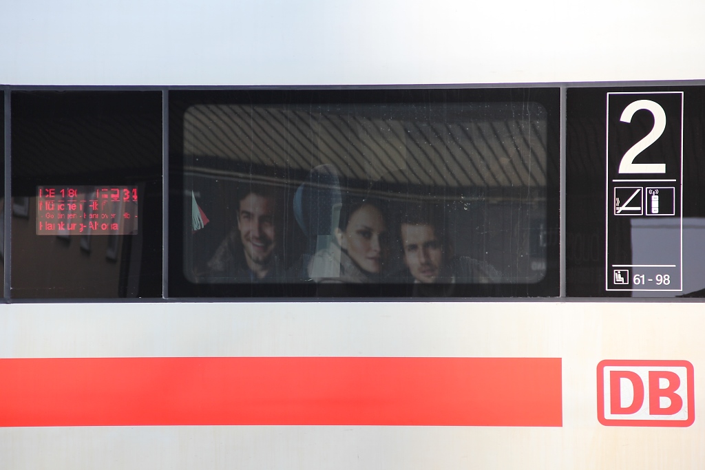 Zufriedene Fahrgste... Aber eigentlich ist es nur ein Werbeplakat fr Klamotten, deren drei Werbefiguren sich beim Halt eines ICE in Fulda im Fenster spiegeln. Aufgenommen am 29.10.2011.