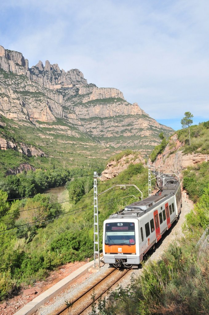 Zug der meterspurigen R5 Vorortbahn zwischen Barelona und Monistrol. Am Berg sieht man das Kloster Montserrat. Dort ist auch die Endstation der ebenfalls meterspurigen Zahnradbahn Monistrol-Montserrat. Sowohl die R5 als auch die Zahnradbahn wird von der FGC betrieben. „Ferrocarrils de la Generalitat de Catalunya“.