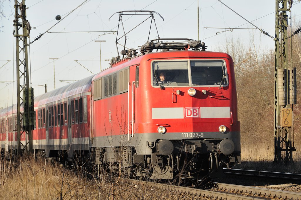 Zur�ckverwandelt: Etwas ungewohnt noch in Verkehrsrot und durch die jetzt direkt �ber der Pufferbohle angebrachte Baureihen- und Ordnungsnummer. 111 027-9 (ex 850 Jahre M�nchen-Jubil�umslok) vor einer RB Richtung Salzburg in Haar bei M�nchen am 3. Dezember 2009