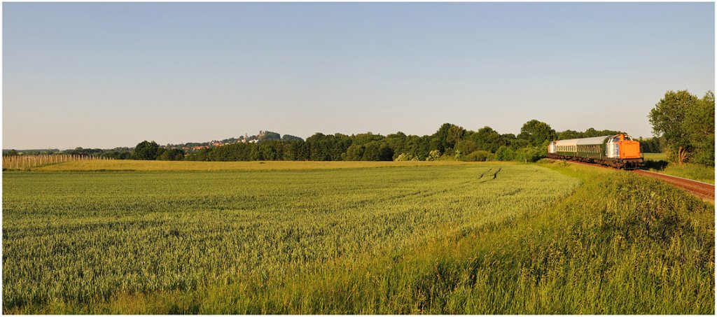 Zwei Bayern zu Gast auf dem S�chsische-Schweiz-Ring:
Wegen des Kirchentages in Dresden hat die St�dtebahn Sachsen ( Betreiber der Strecken zwischen Pirna-Neustadt und Bad Schandau ) Triebwagen des Typs Desiro auf Strecken rund um Dresden zur Verf�gung gestellt. Und so kam es , dass mit den zwei V 100 ( West ) der Nordbayerischen Eisenbahn und zwei Reisezugwagen der Reichsbahn rund 10 Jahre nachdem die letzten Lokbespannten Z�ge auf diesen Strecken fuhren endlich wieder ein solches Gespann im Plantakt unterwegs ist. Noch bis Sonntag ist die Garnitur mehrmals am Tag auf den romantischen Strecken unterwegs. Ein Ausflug lohnt sich, auch in einigen St�dten an der Bahn gibt es am Wochenende ein interessantes Programm - so z.B. in Neustadt / Sachsen zum Stra�enfest oder in Stolpen zum historischen Stadtfest.
Die Zukunft des S�chsische-Schweiz-Rings ist weiterhin ungewiss, wer hier also nochmal   echten   Diesel erleben will sollte sich das nicht entgehen lassen ;-)
Foto: Am Abend des 03.Juni hat das Gespann soeben Helmsdorf verlassen und schraubt sich durch eine Steigung der Burgstadt Stolpen entgegen, die man im Hintergrund schon erkennen kann.
03.06.2011 / 19:35 Uhr